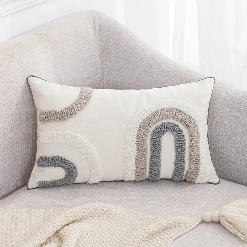 Cream-colored rectangular cushion cover with textured boho tufted embroidered rainbow design in grey and beige