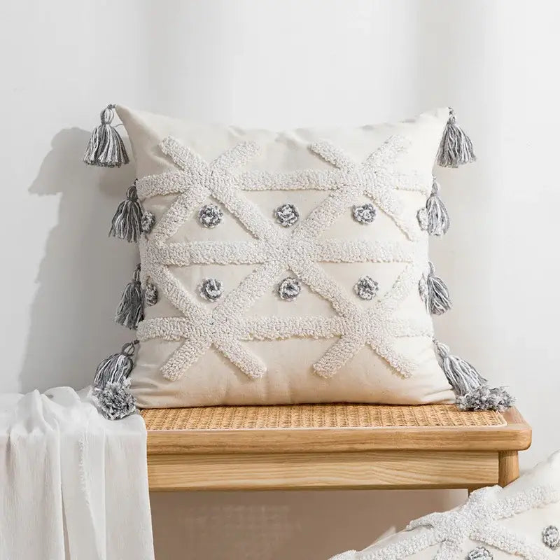 Cream-colored boho tufted embroidered cushion cover with white crosshatch texture and silver tassels for living room decorbites