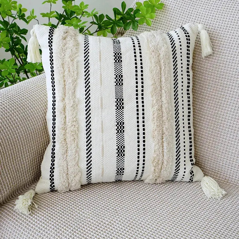 A cozy off-white and black woven boho tufted fringed black throw pillow with textured stripes and tassels for decorbites decor
