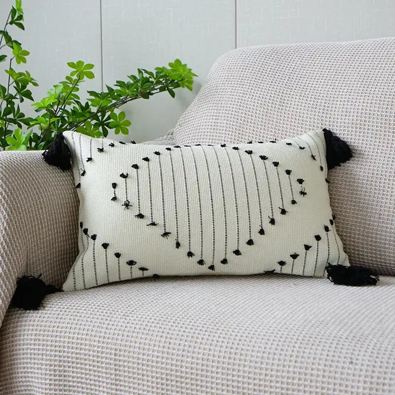 Cream-colored rectangular boho tufted fringed pillowcase with black vertical stripes and tassel accents for living room decor