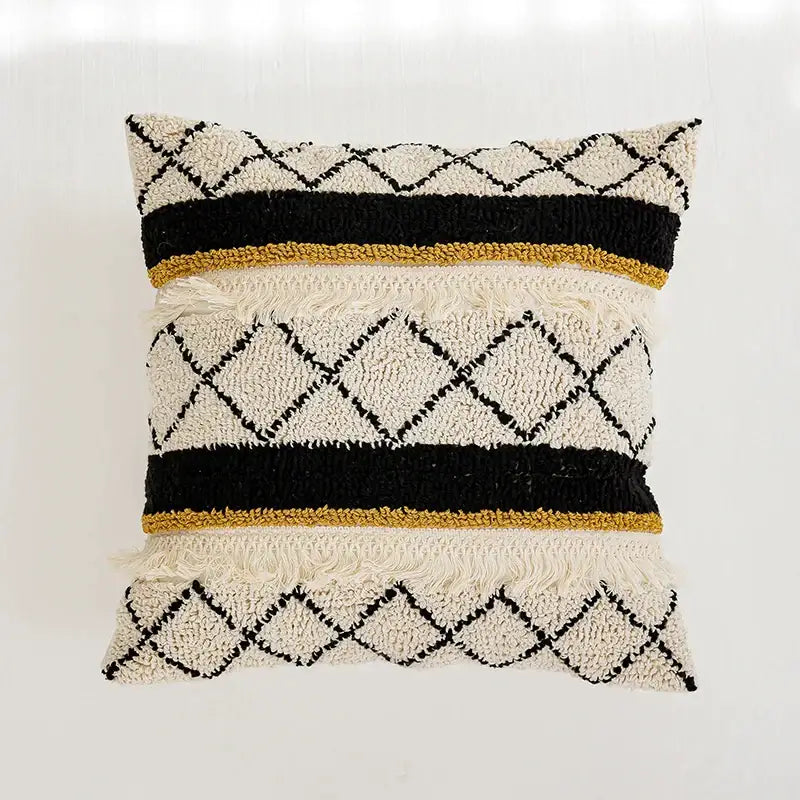 Cream-colored boho tufted pillow cover with black and mustard-yellow geometric patterns and fringed edges by decorbites
