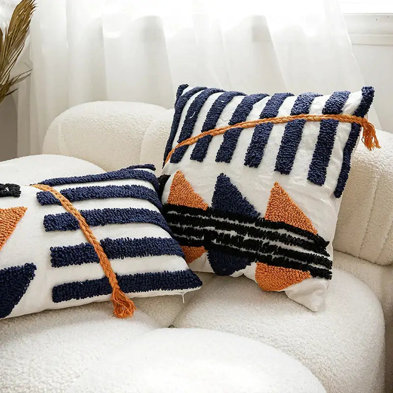Two boho tufted pillow covers in navy and burnt orange with chunky yarn tufts and braided tassels for living room decorbites decor