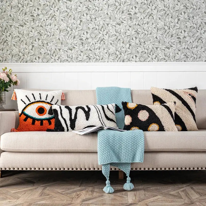 A cozy beige sofa with colorful throw pillows and a boho white and black decorbites black abstract eye pillow cover