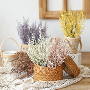 A woven boho wicker basket with a lid filled with pink and white decorbites forever dancing grass flowers