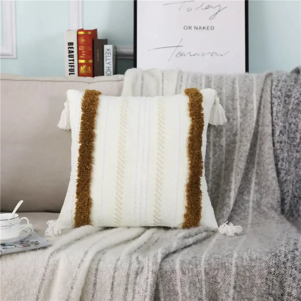 Cream-colored decorbites boho woven pillow case with textured vertical stripes and brown tassel accents for living room decor