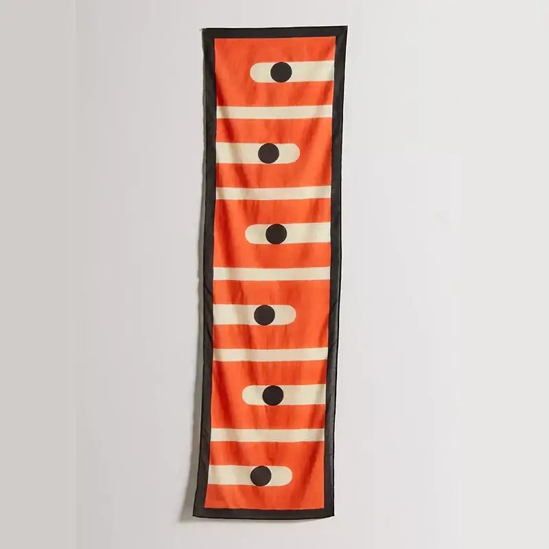 A vibrant orange silk scarf with bold white stripes black accents and a black border featuring celestial geometry design
