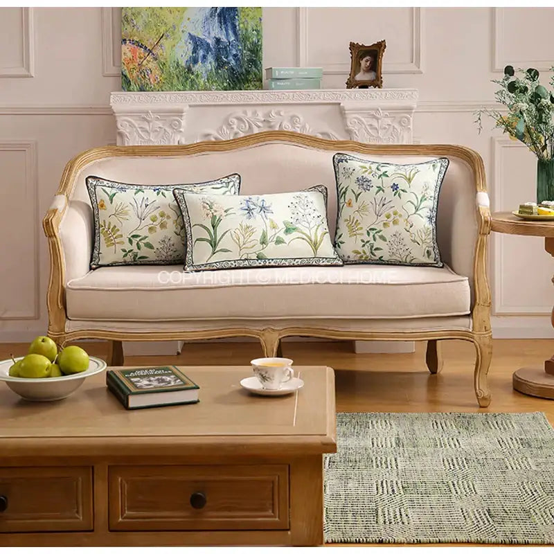 Beige upholstered sofa with ornate gold-toned wooden frame and three botanical leaf watercolor linen lumbar pillowcases