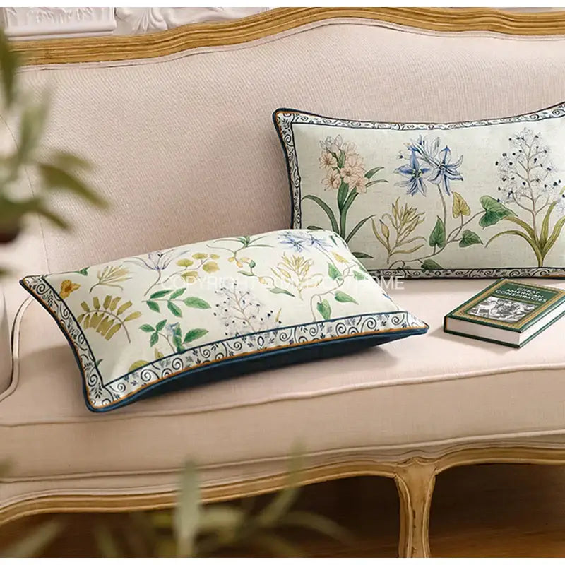 Two rectangular linen throw pillows with botanical leaf watercolor embroidery in pastel tones and dark ornate borders