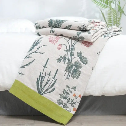 A soft cream-colored decorbites cotton leisure blanket with botanical print and lime-green border for bedroom use