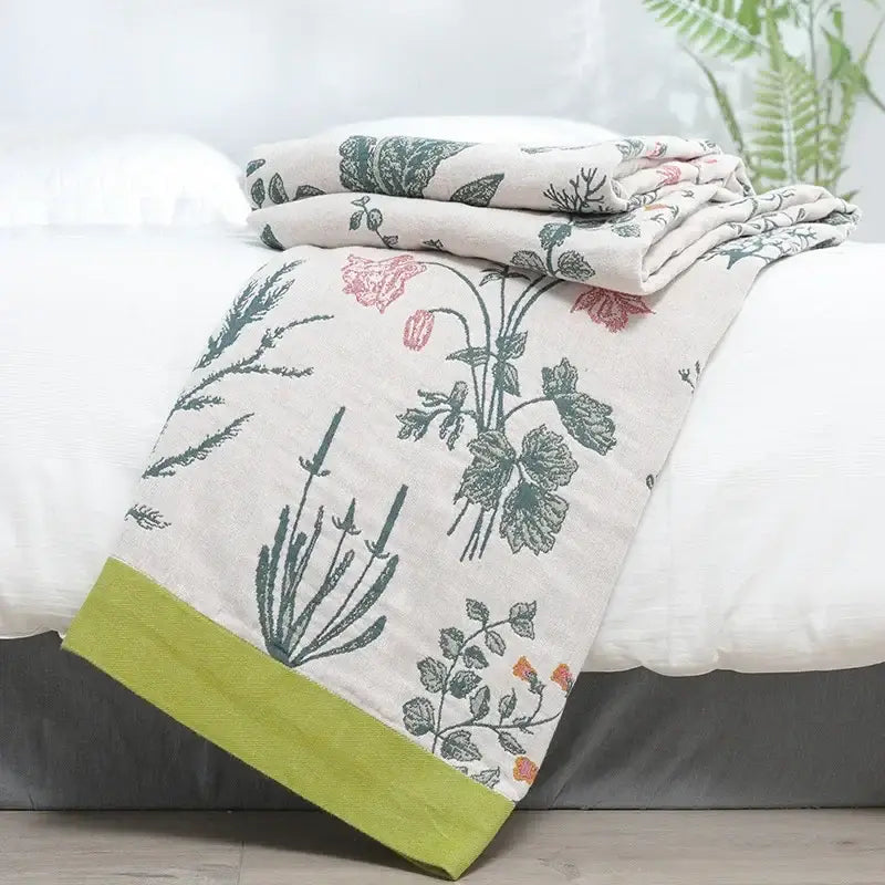 A soft cream-colored decorbites cotton leisure blanket with botanical print and lime-green border for bedroom use