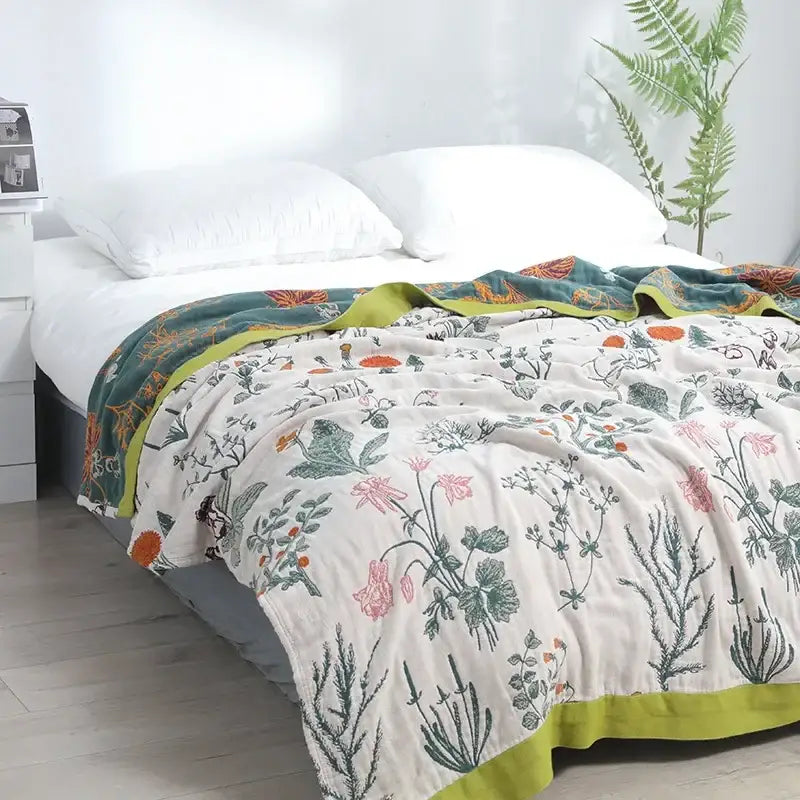 A soft off-white decorbites cotton leisure blanket with delicate pink and green botanical print and lime-green border