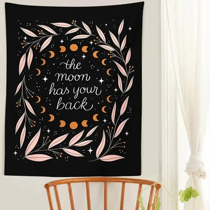 Black wall tapestry with botanical olive leaf moon phases in pink and gold featuring the phrase the moon has your back