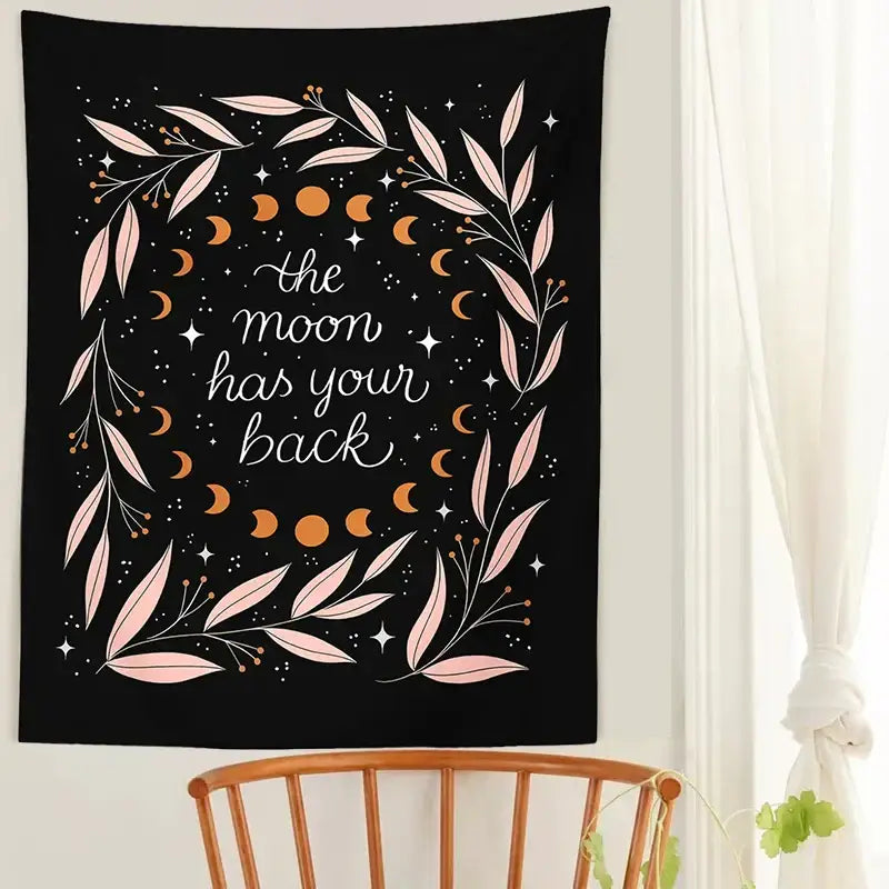 Black wall tapestry with botanical olive leaf moon phases in pink and gold featuring the phrase the moon has your back