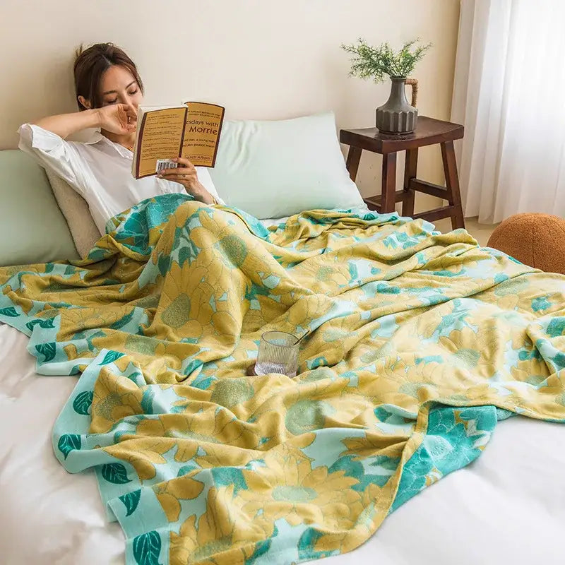 Botanical white and gray bamboo four layer summer quilt draped over a person with vibrant yellow and teal floral pattern