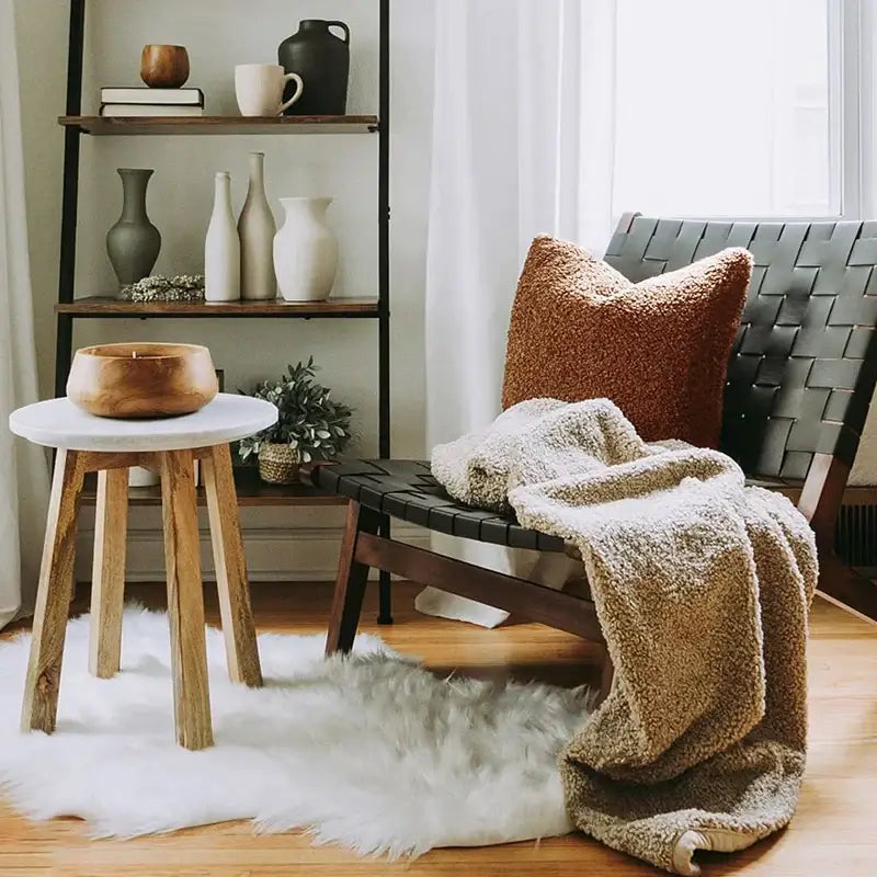 A rustic wooden bowl with a natural finish on a white marble stool in a decorbites boucle teddy throw pillow living room set