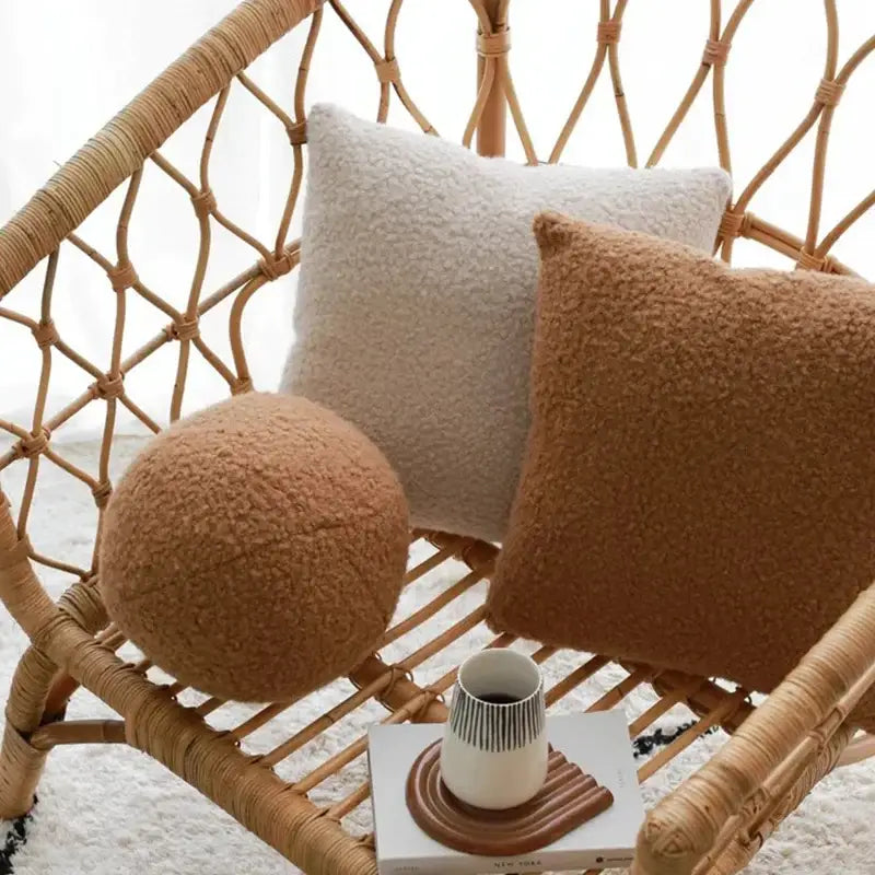 Cream and tan boucle teddy throw pillows with soft textured surface on woven rattan chair for living room decorbites boucle teddy