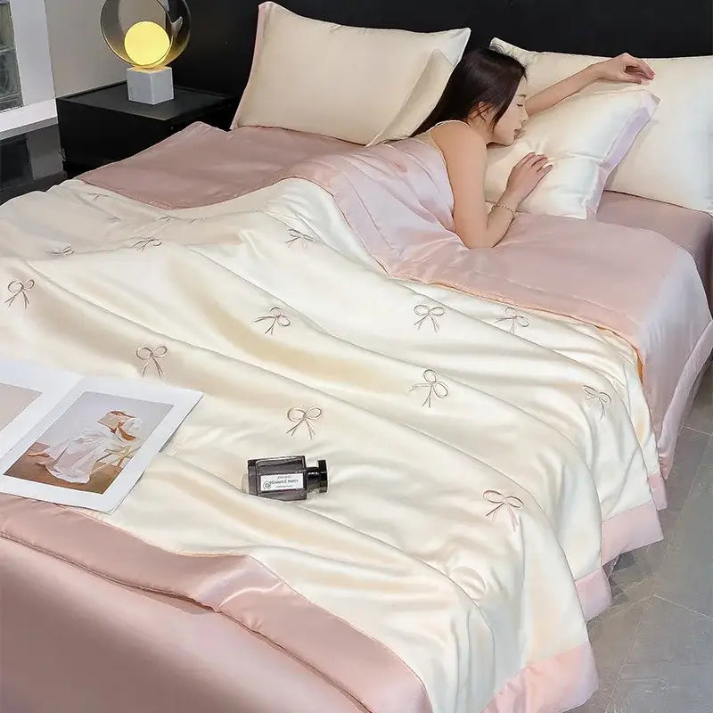 Cream-colored satin quilt with delicate silver bowknot embroidered and soft pink trim in decorbites bowknot embroidered summer bedding set
