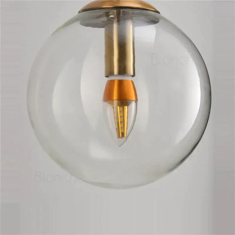 Brass amber glass ball wall light with clear globe pendant, brass fixture, and orange led bulb for bedroom decorbites glass ball
