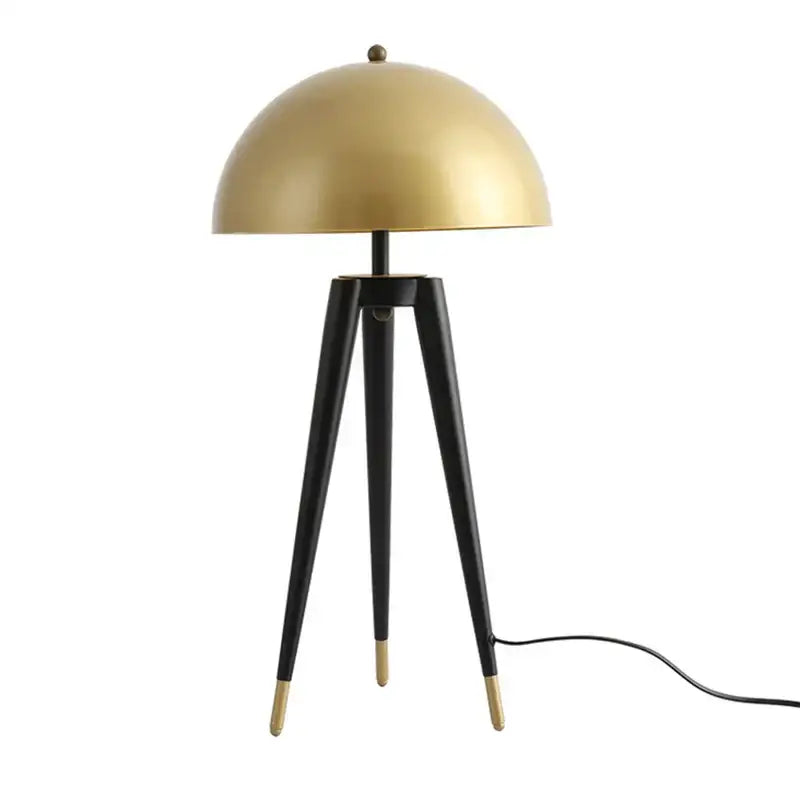 A sleek gold dome floor lamp with black brass-tipped legs and coyote gold tripod base from Decorbites