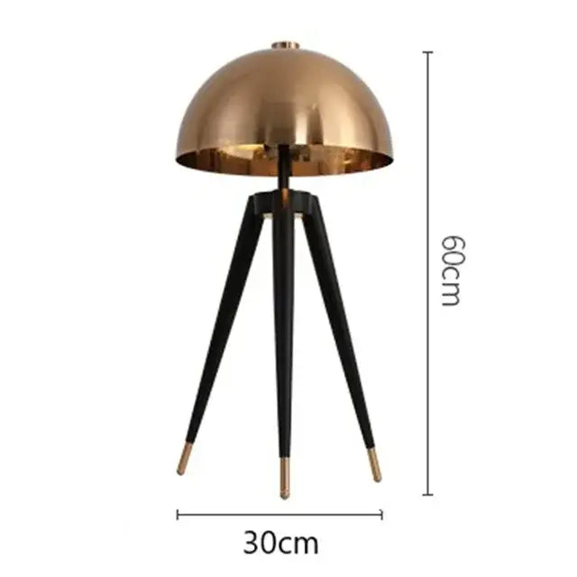 A sleek brass and black floor lamp with decorbites coyote gold tripod legs and gold-tipped feet, 60cm tall