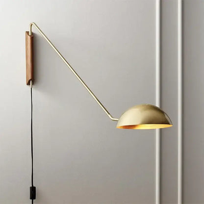 Gold-toned adjustable metal wood wall lamp with sleek articulated arm and wooden backplate for bedroom reading light