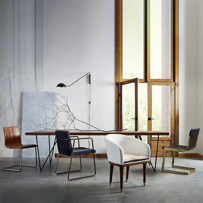 White upholstered armchair with wooden legs and cushioned seat beside a brass and wood adjustable metal wood wall lamp