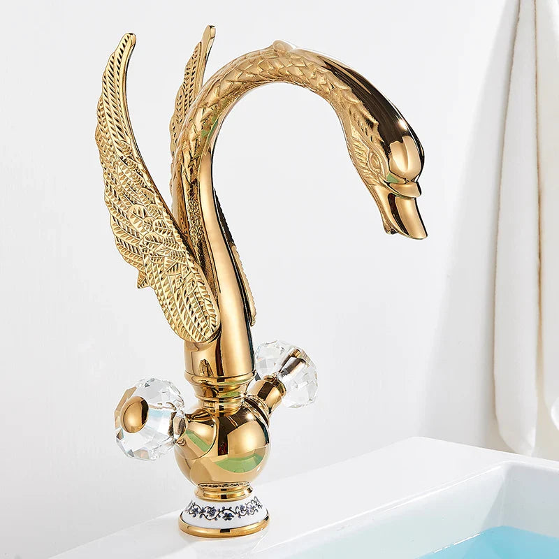 Brass basin faucet deck mounted featuring an antique brass golden swan shape with intricate feather detailing and crystal knobs