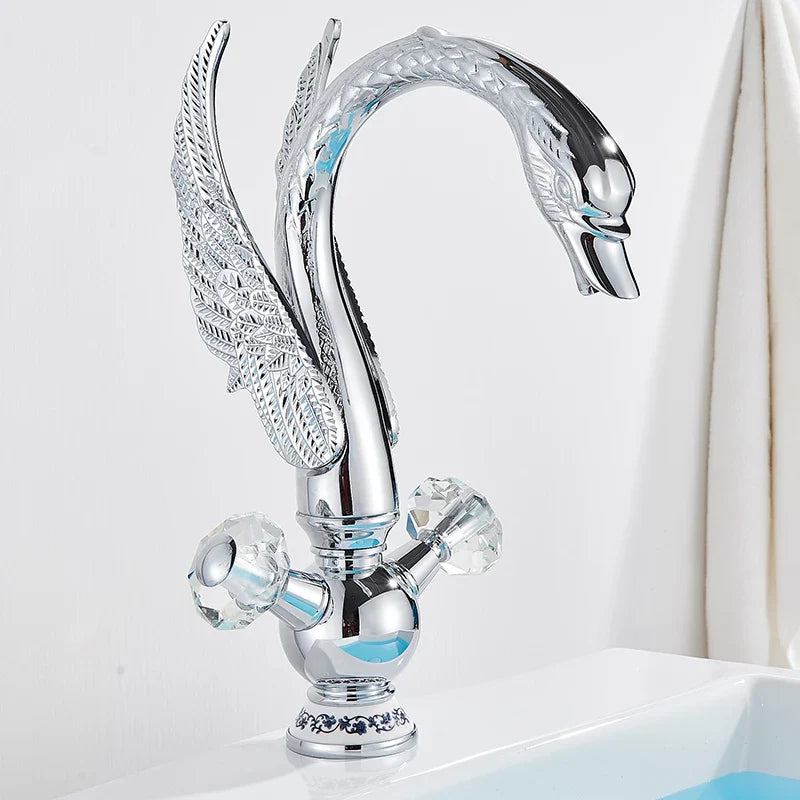 Brass basin faucet deck mounted with sleek chrome swan design, intricate wings, and crystal knobs, antique brass finish