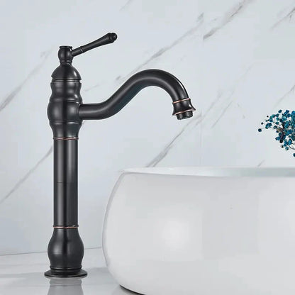 Brass bathroom basin mixer faucet with black matte finish, curved spout, ornate handle, and subtle copper accents
