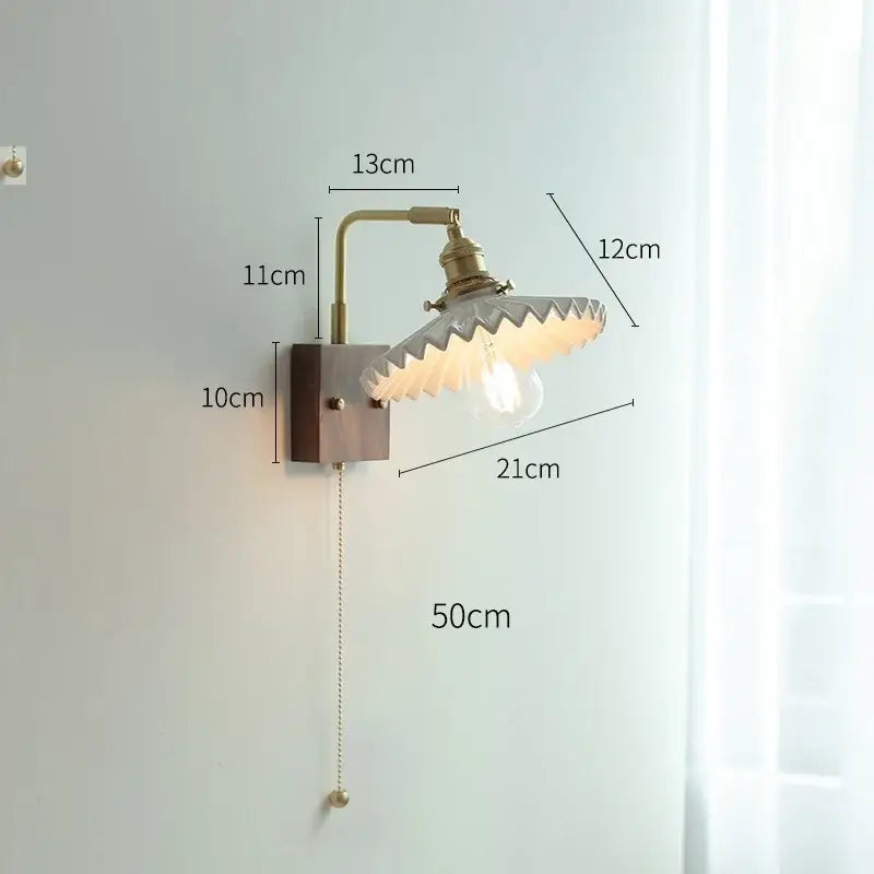 Antique brass-finished led wall light with scalloped translucent glass shade and exposed bulb for living room use