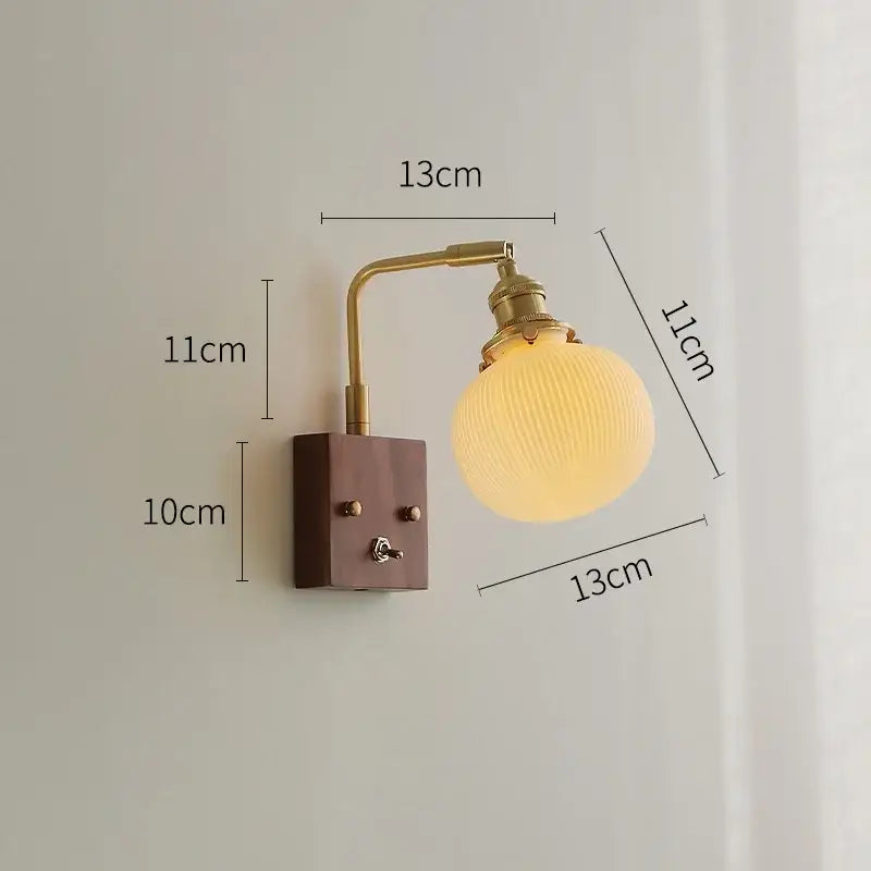 Brass ceramic ball led wall light with a yellow ribbed glass globe and brass arm mounted on dark wood for living room
