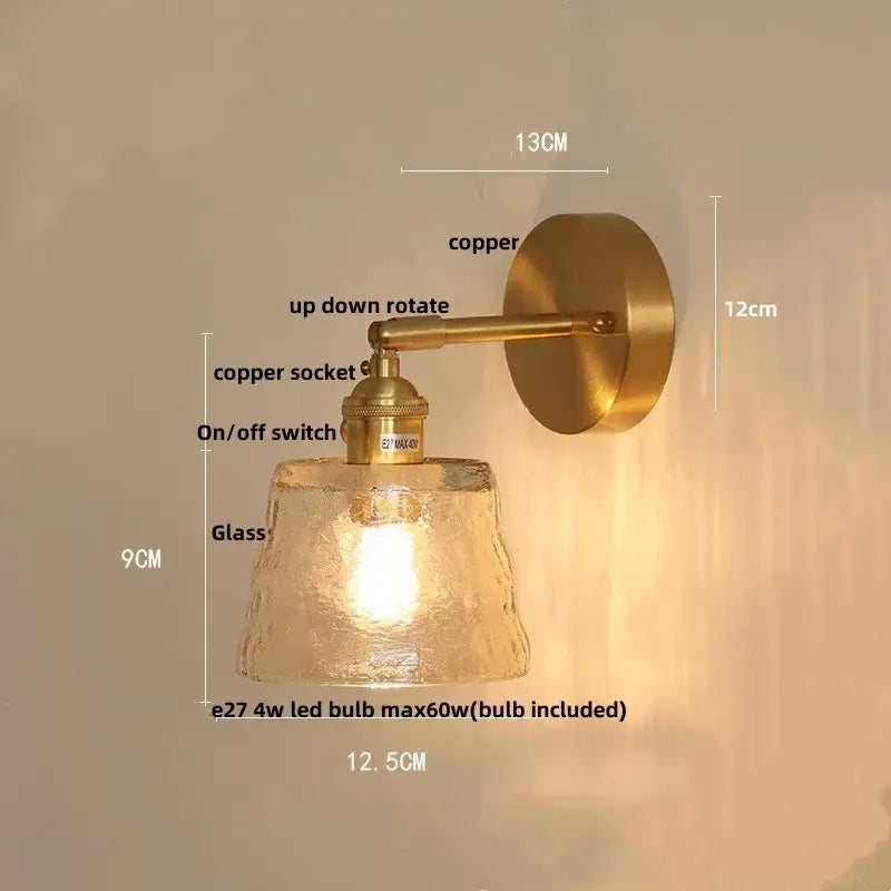 A warm-toned brass clear glass led wall sconce with a textured frosted shade and adjustable arm by decorbites