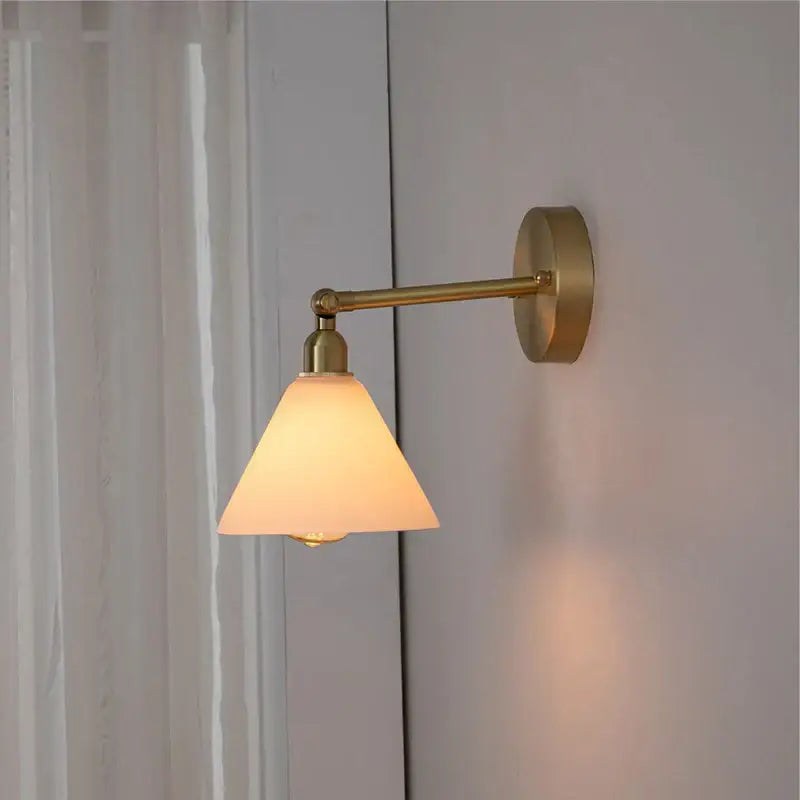 Warm-toned brass wall light with frosted clear glass conical shade and pull chain for bedroom reading decorbites clear glass
