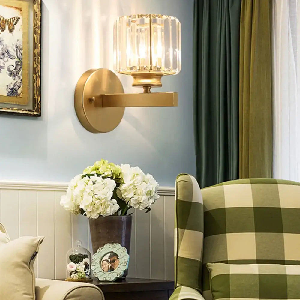 Gold-toned brass wall sconce with faceted decorbites crystal glass shade for elegant bedroom lighting