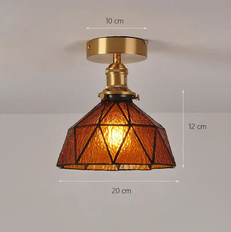 A warm amber glass shade pendant ceiling lamp with brass finish and geometric triangular patterns for kitchen lights