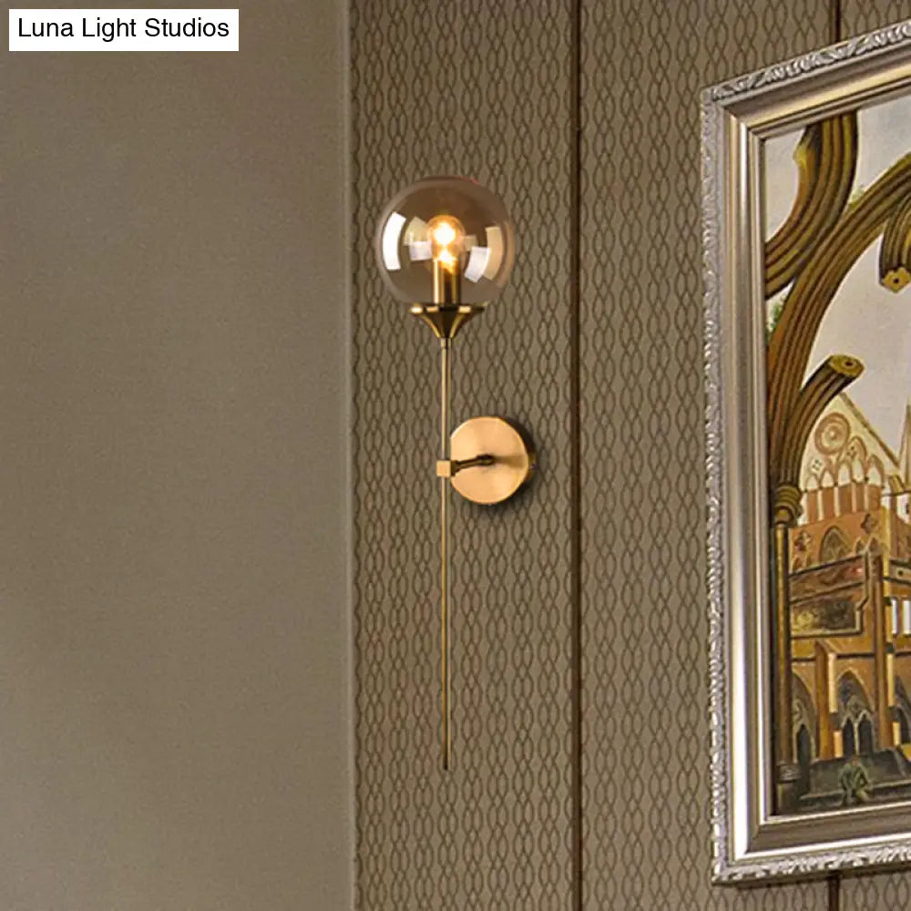 Aplique de pared con pantalla esférica de latón - Luz moderna de un solo foco con cristal transparente/gris/ámbar para dormitorio