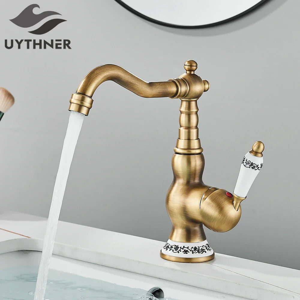 Antique brass finished deck mounted bathroom faucet with rotating neck and ornate white ceramic handles with black floral patterns