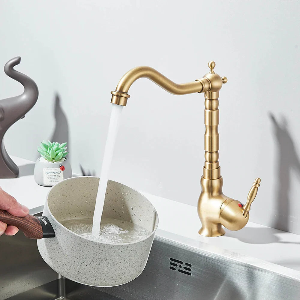 Brass kitchen faucet deck mounted with rotating neck curved spout and ornate segmented body design in brass finish