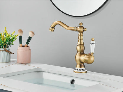 Deck mounted brass kitchen faucet with antique brass finish ornate detailing and white ceramic handles with black floral engraving