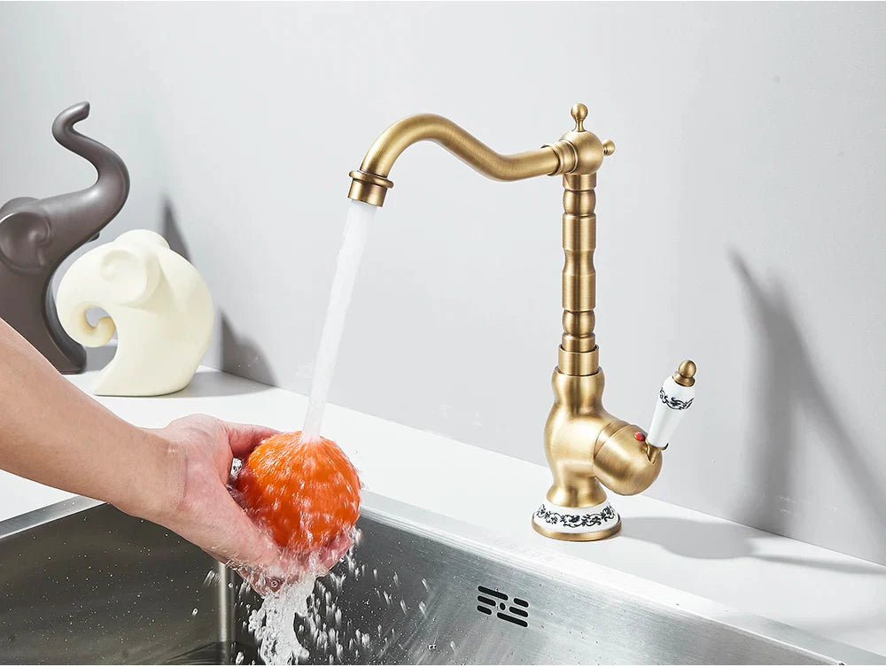 Antique brass finished deck mounted kitchen faucet with rotating segmented spout and ceramic handle accents