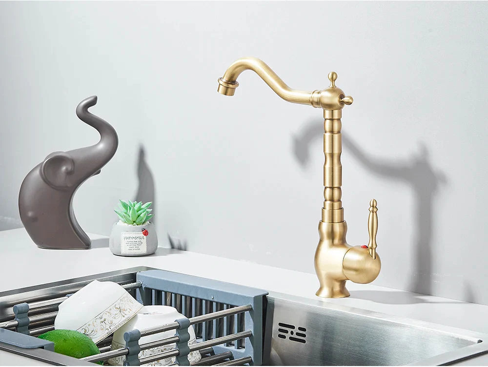 Brass kitchen faucet with rotating neck deck mounted featuring brass finish curved spout and ornate segmented design