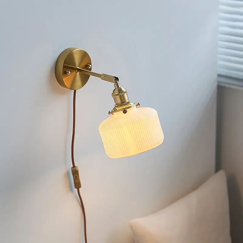 Brass ribbed decorbites ceramic wall sconce with iron arm and off-white glass shade for bedroom lighting