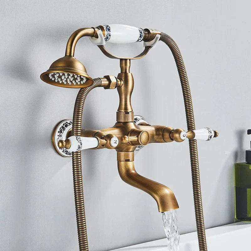 Antique brass shower faucet wall mount with white ceramic handles, decorative black floral patterns, fixed showerhead, and cold water control