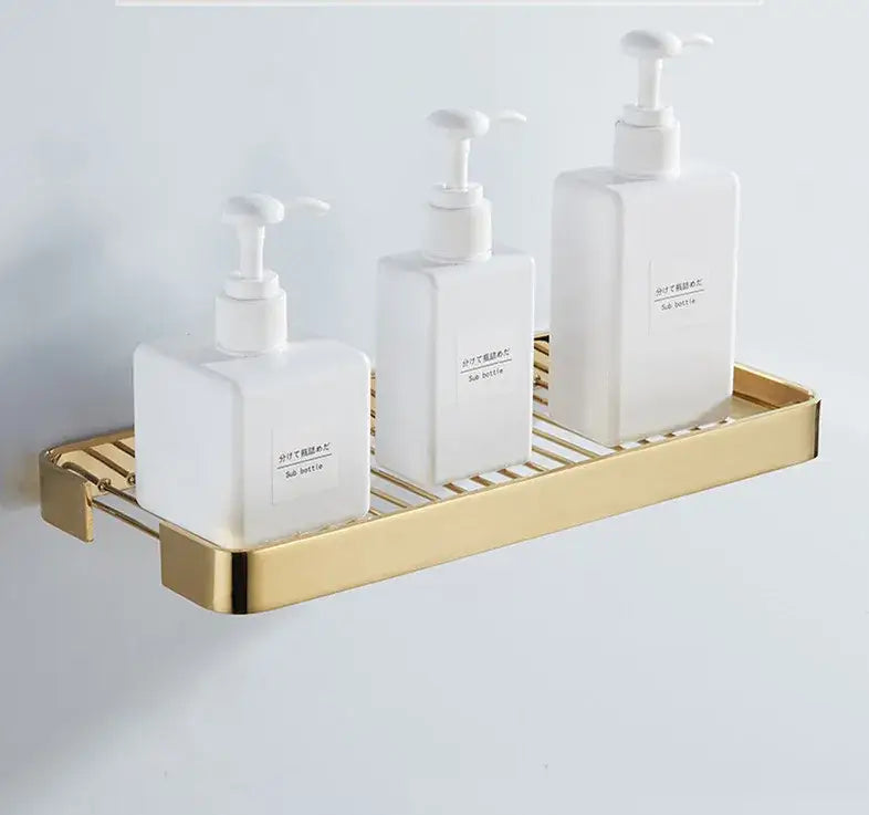 Gold-toned metal decorbites brass square bathroom slatted shelf holding three white rectangular soap dispensers