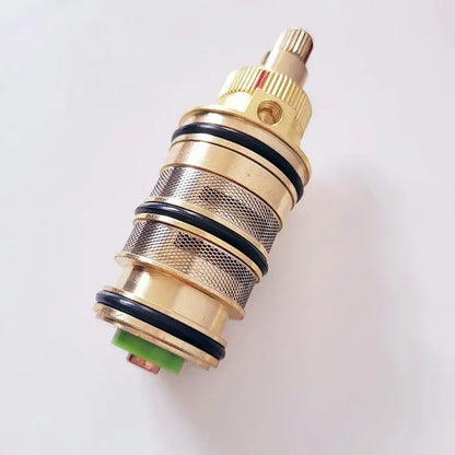 Gold-colored brass thermostatic mixer cartridge with black rubber seals and textured mesh pattern for kitchen use decorbites brass thermostatic