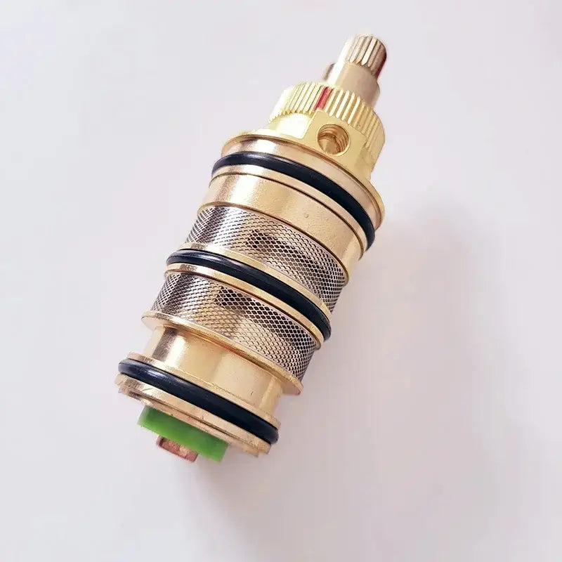 Gold-colored brass thermostatic mixer cartridge with black rubber seals and textured mesh pattern for kitchen use decorbites brass thermostatic