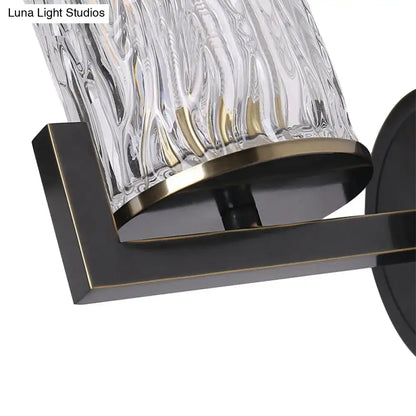 Brass wall light featuring a textured cylinder rippled glass lampshade with bronze trim and black metal bracket