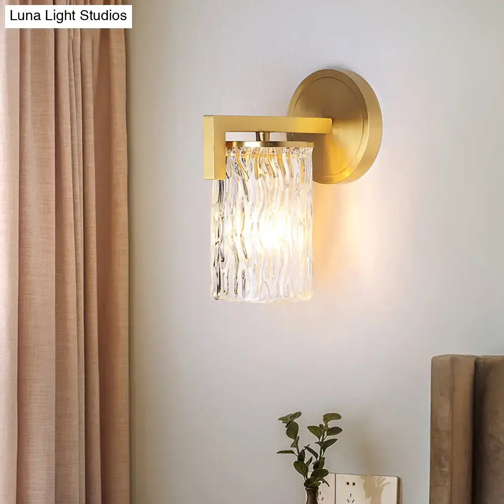 Gold-finished brass wall light with cylinder rippled glass shade featuring vertical ridges for bedroom sconce lighting