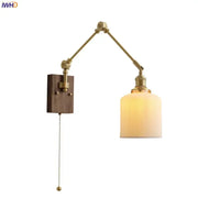 Brass adjustable wall sconce with copper swing arm, ribbed cream glass shade, and wooden mounting plate for bedroom lighting