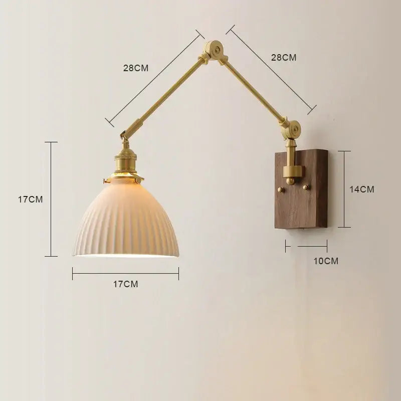 A brass finished adjustable wall sconce with copper swing arm led, ribbed off white glass shade, and walnut backplate